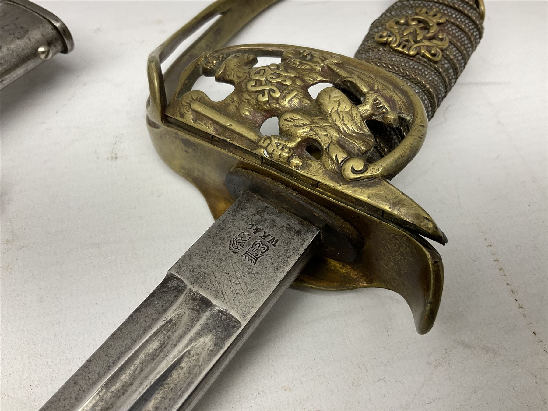 19th Century Prussian Infantry Officers 1889 pattern sword, the 77.5cm double fullered blade with makers mark to the ricasso for Weyersberg Kirschbaum & Co; curved brass top pommel with brass wire bound fish skin grip applied with crowned  Wilhelm II monogram; folding cross guard with Imperial eagle and double bar knucklebow; in polished steel scabbard with single suspension ring L94.5cm overall