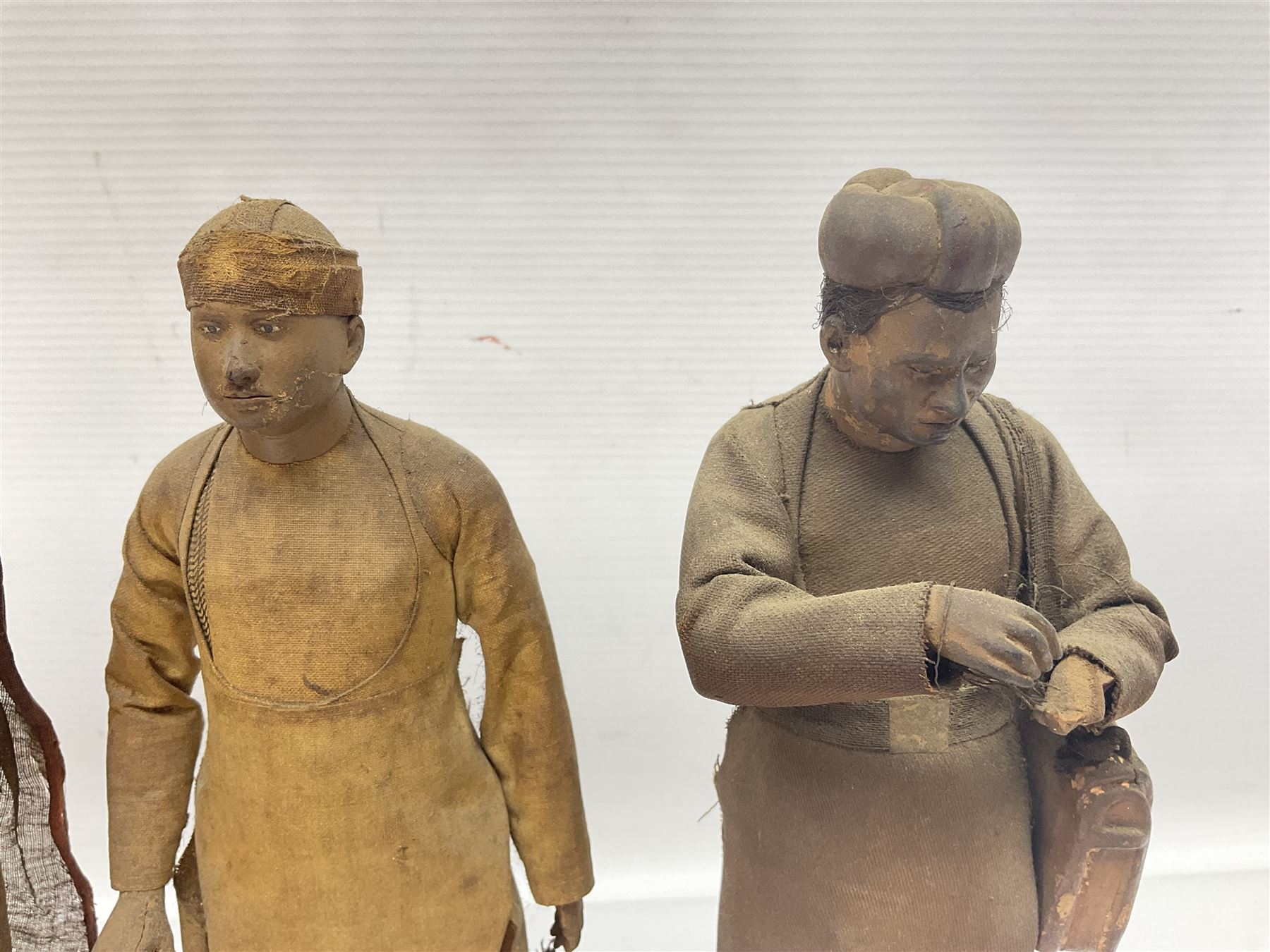 Seven 19th Century Indian clay dolls, possibly Krishnanagar, each figure with painted details, wearing cloth garments, standing on rectangular bases, some with paper label to the base, H25cm