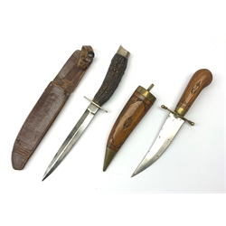 Fighting knife with 15cm steel double edged blade, nickel crosspiece and antler grip with hallmarked silver butt Sheffield 1910, in leather sheath pin pricked with the name F. Hanson L28cm overall; and an Eastern jambiya dagger with brass and carved hardwood hilt and scabbard (2)