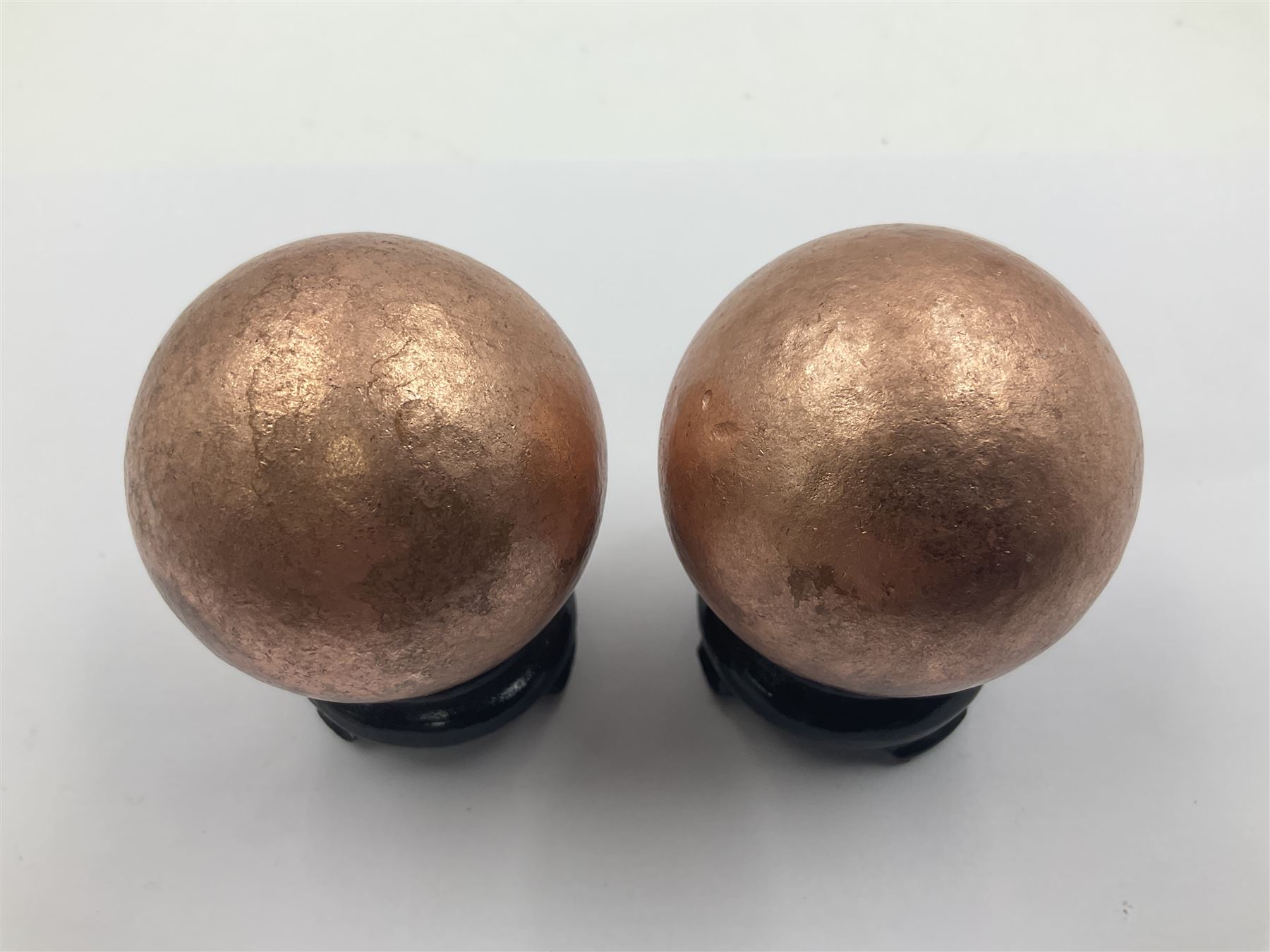 Pair of copper spheres, upon carved wooden bases, D5cm 