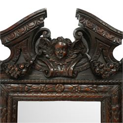 Renaissance-style mid 19th century carved fruitwood wall mirror, carved top surmounted by ‘broken’ arched pediment with central putti figure and grape vine, the sides with two putti figures above C-scroll decorations, and with a similarly carved base