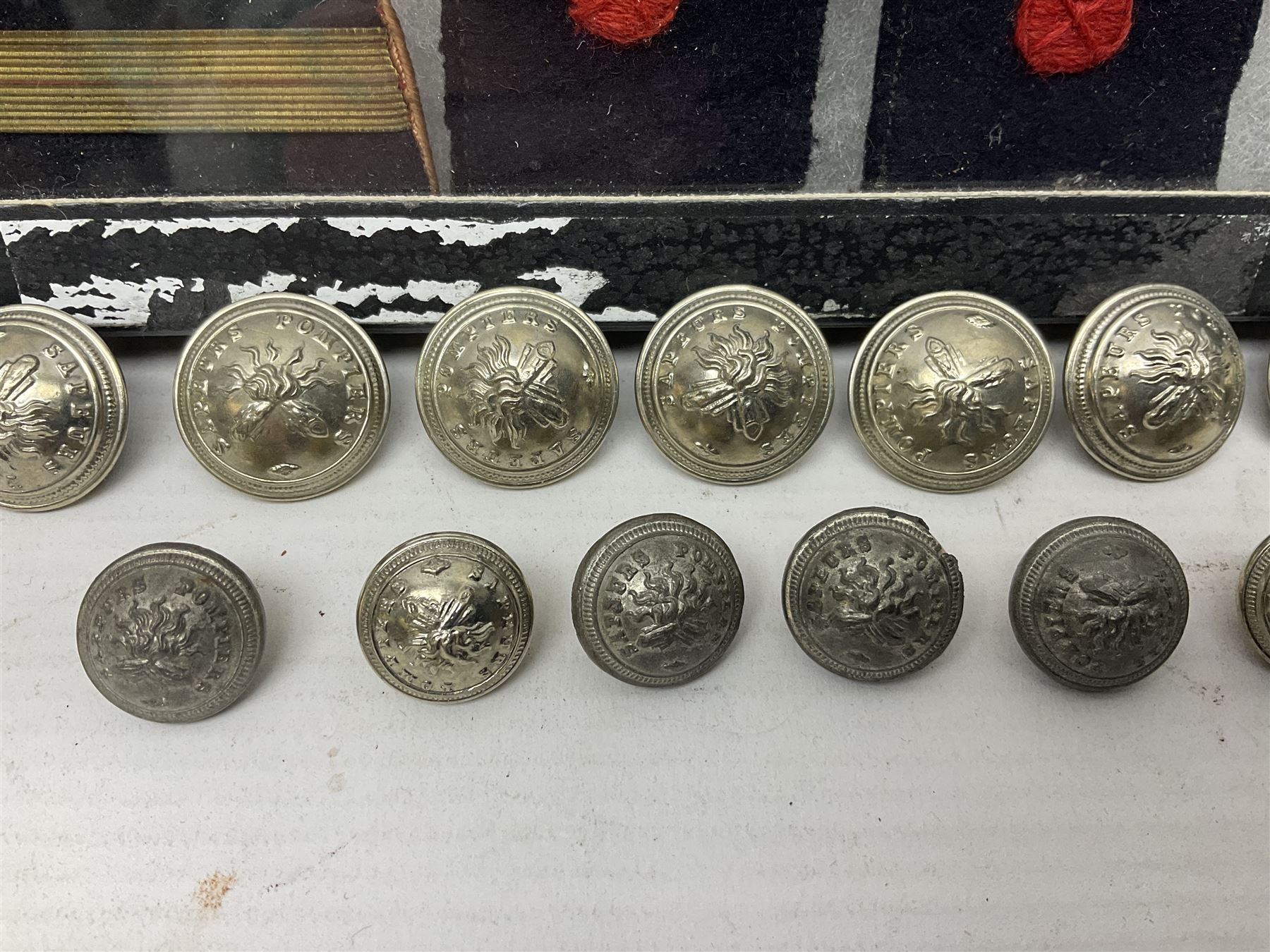 Over thirty items of French Sapeur Pompiers (Fire Service) cloth insignia and buttons c1930s/40s; in small glazed display case