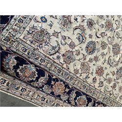 Large Persian Heriz carpet, ivory ground with trailing floral design and decorated with stylised flower heads, matching design to blue ground boarder, multiple guards with foliate decoration 