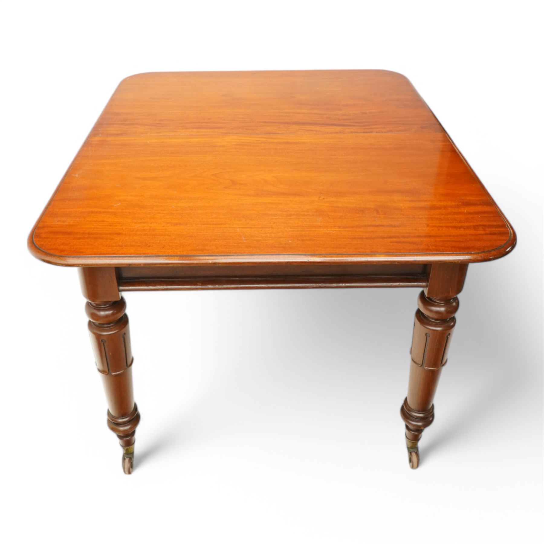 Victorian mahogany extending dining table, moulded rectangular top with rounded corners, pull-out action with additional leaf, on turned and lappet carved supports terminating to brass and ceramic castors 
