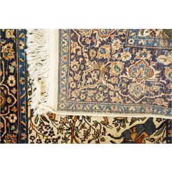 Persian pictorial rug featuring a hunting scene, ivory field with mounted hunters, animals, birds and trees, rich navy and terracotta floral border with rosettes and palmettes 