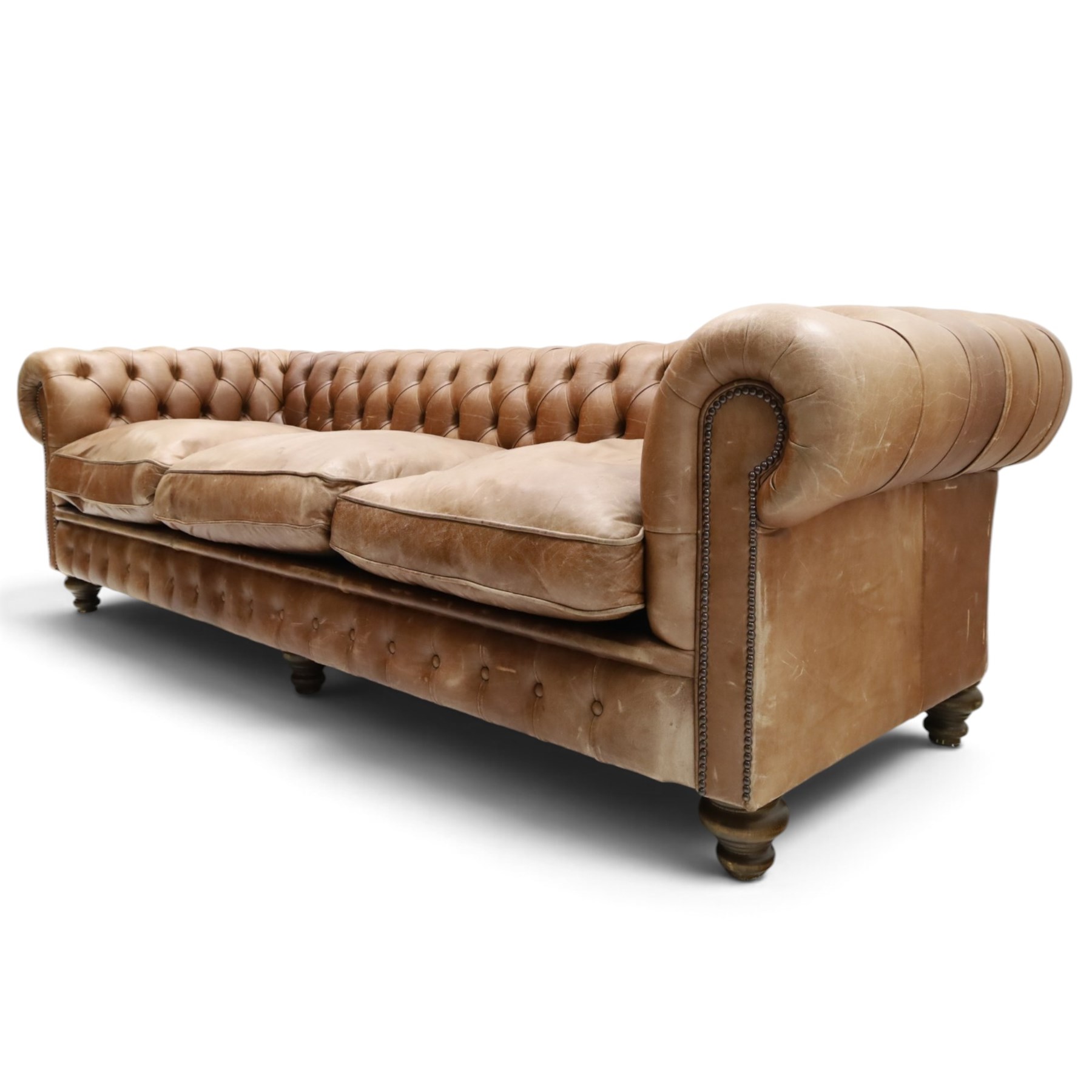 Fleming & Howland Ltd - large traditional shape four seater chesterfield club sofa, the rolled ack and arms with studwork, upholstered in buttoned tan leather with loose seat cushions, raised on large turned feet