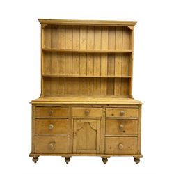 Victorian pine dresser base, fitted with seven drawers with turned handles, flanking central panelled cupboard, with two-tier plate rack