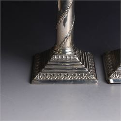 Pair of Edwardian silver mounted column candlesticks, each with embossed floral, foliate and scrolling decoration and upon stepped square weighted bases, hallmarked William Hutton & Sons Ltd, London 1901, H19cm