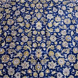 Central Persian Kashan hand-knotted carpet, deep indigo blue field densely decorated with all-over vine, palmette and flowering sprays arranged in a symmetrical pattern enclosed by broad navy border of stylized palmettes, and foliate vine decoration between multiple guard stripes, with cotton fringe ends 