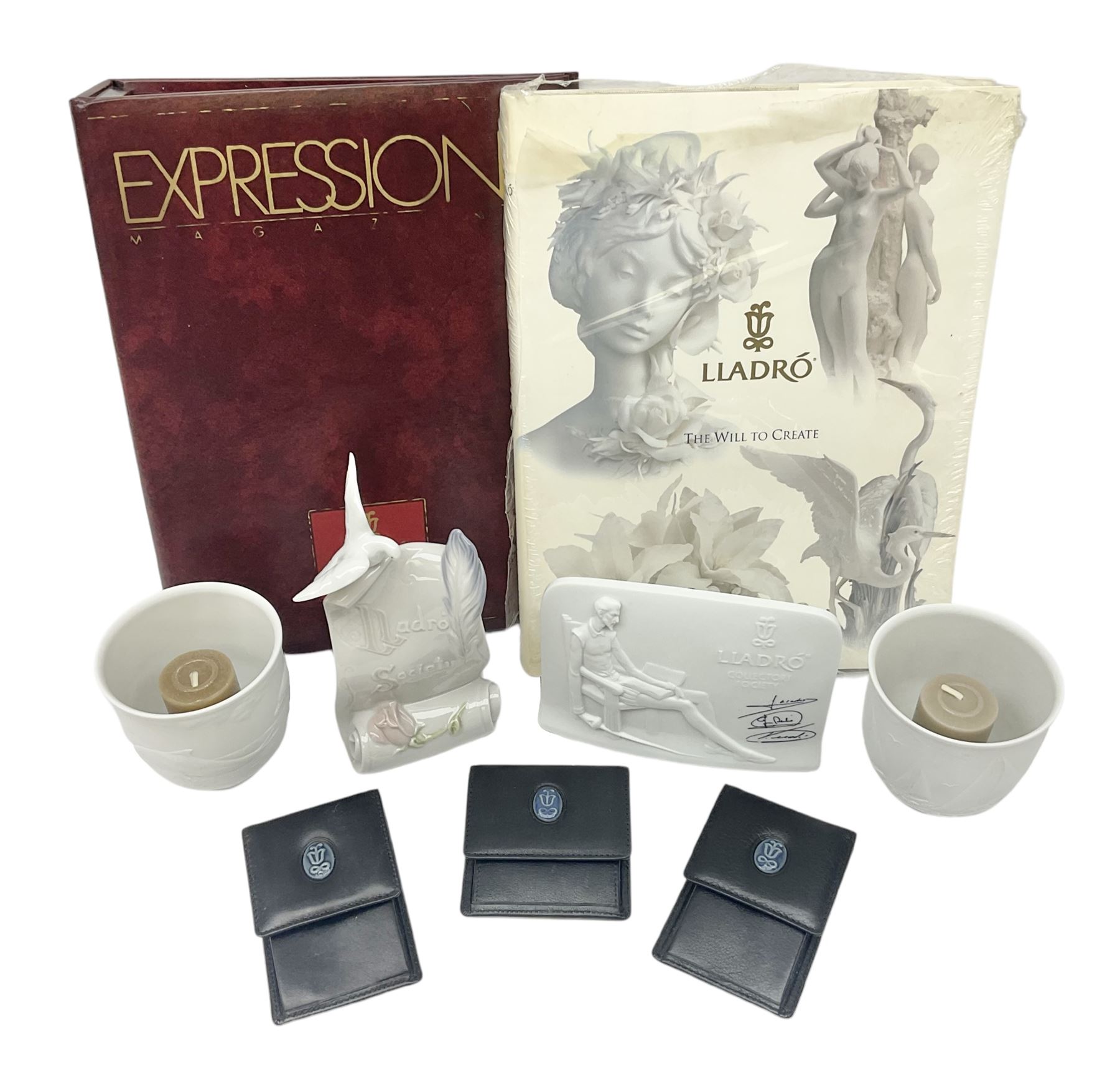 Lladro Collectors Society items, comprising of The Will to Create book, two candle holders; Sailing the Sea no 17665, Dolphins at Play no 17666, Plaque Bringing Us Together, key fob, leather wallet and a members joining pack with plaque, all in original boxes  
