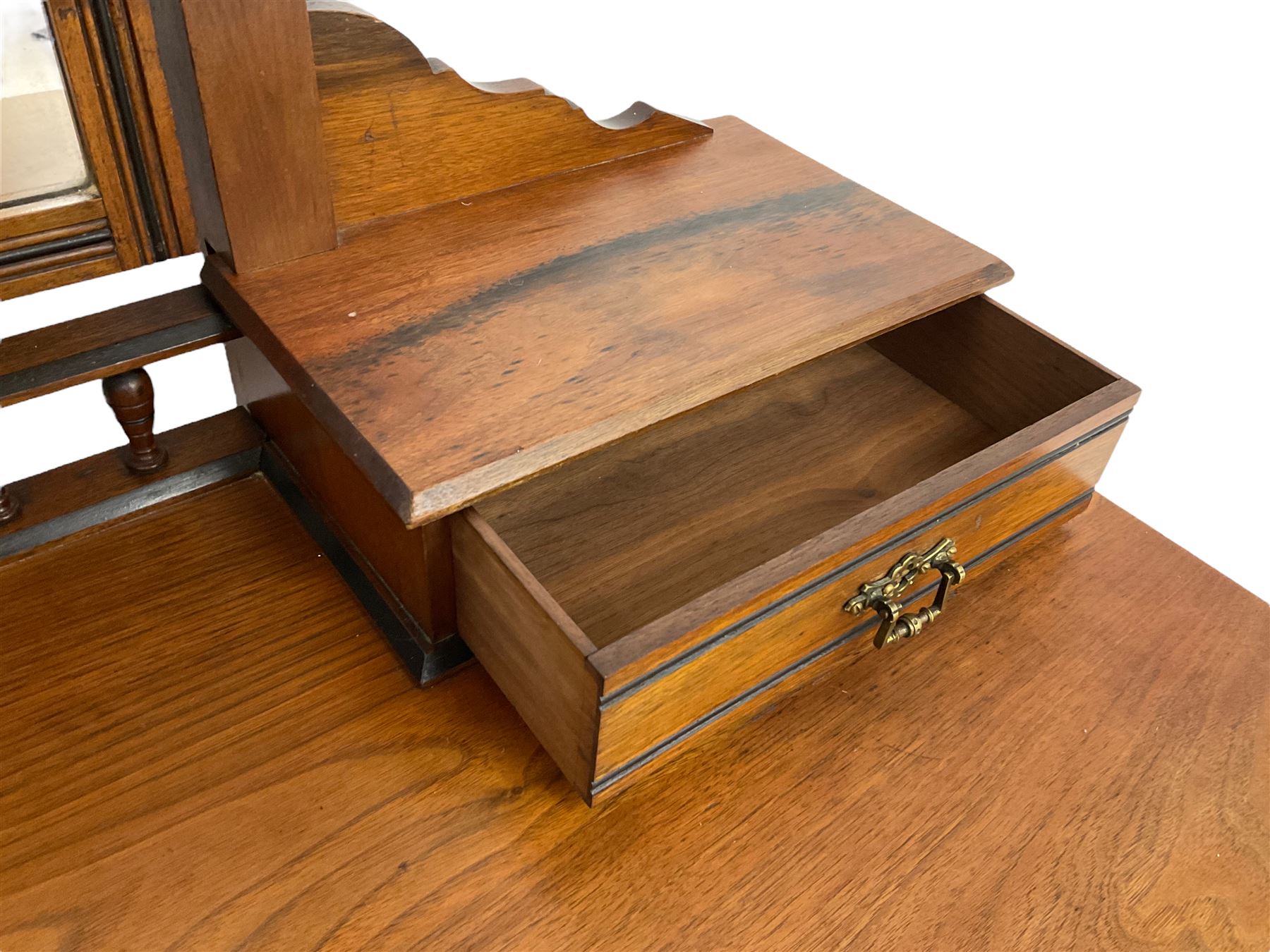Late Victorian Aesthetic Movement walnut and inlaid ebony dressing table, swing mirror back with shell carving and spindle support rail, fitted with two trinket drawers and single frieze drawer, raised on ring turned supports with castors
