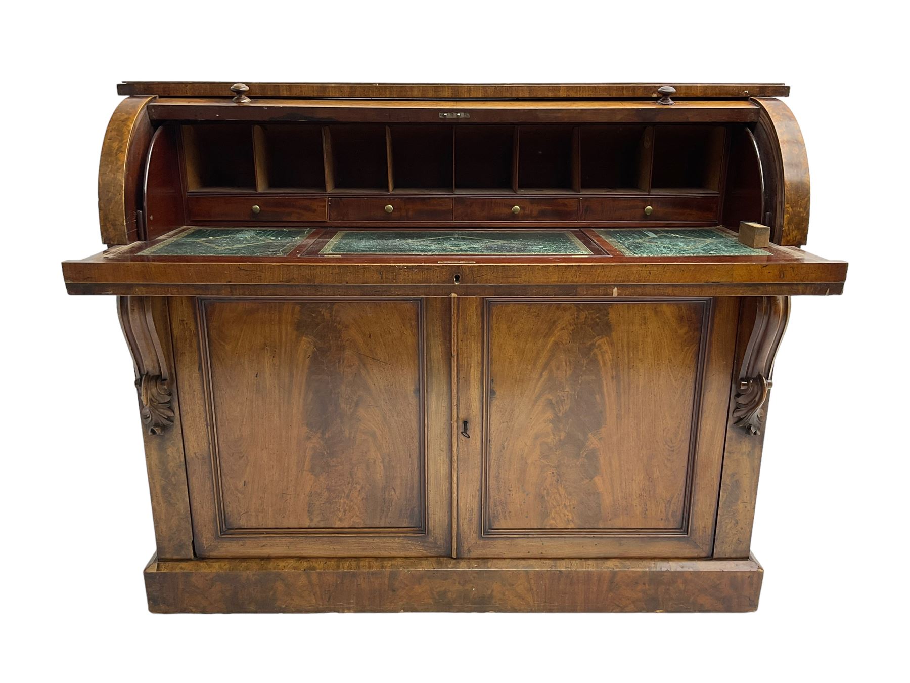 Victorian mahogany roll-top writing desk, top concealing fitted interior with pigeonholes and three drawers, the trisector inset writing surface with writing slope, base fitted with panelled cupboard enclosing single shelf, decorated with scrolled corbels