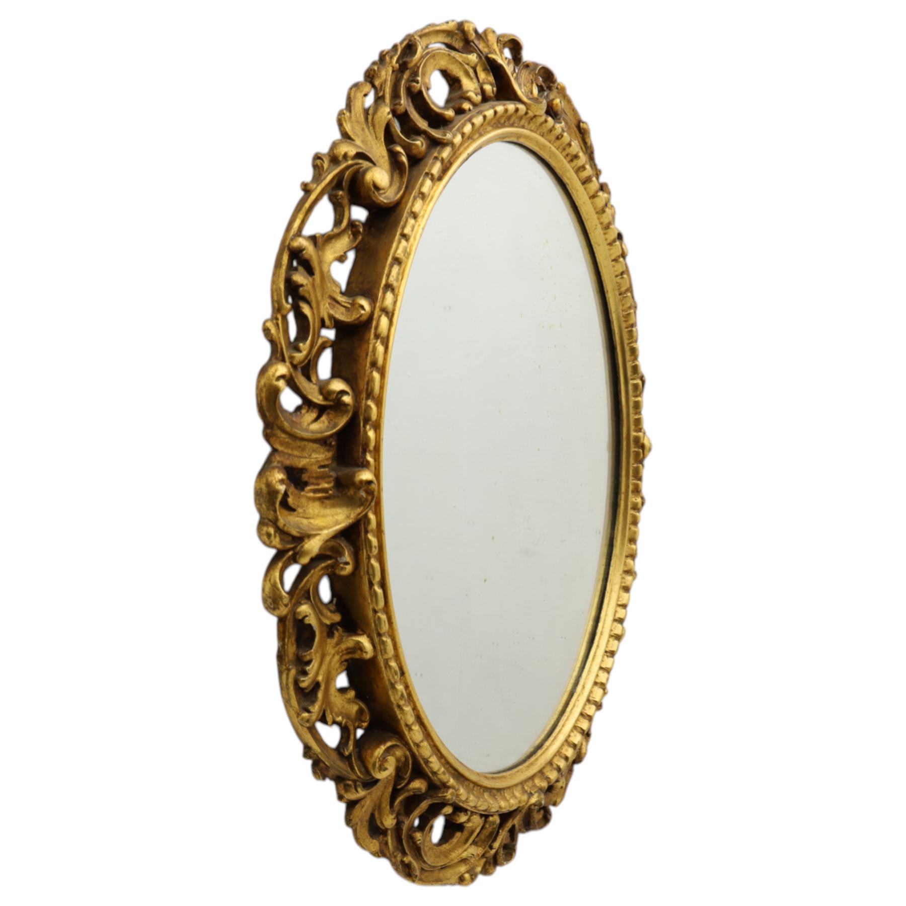 Late 19th century giltwood oval wall mirror, the bevelled plate within a gadroon moulded inner slip, surrounded by pierced scrolling foliate and acanthus carved frame, richly gilded with worn patina indicative of age and use