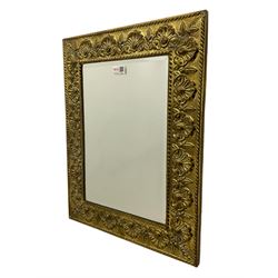 Early 20th century wall hanging mirror, in embossed brass frame decorated with shells and foliate motifs, bevelled mirror plate 
