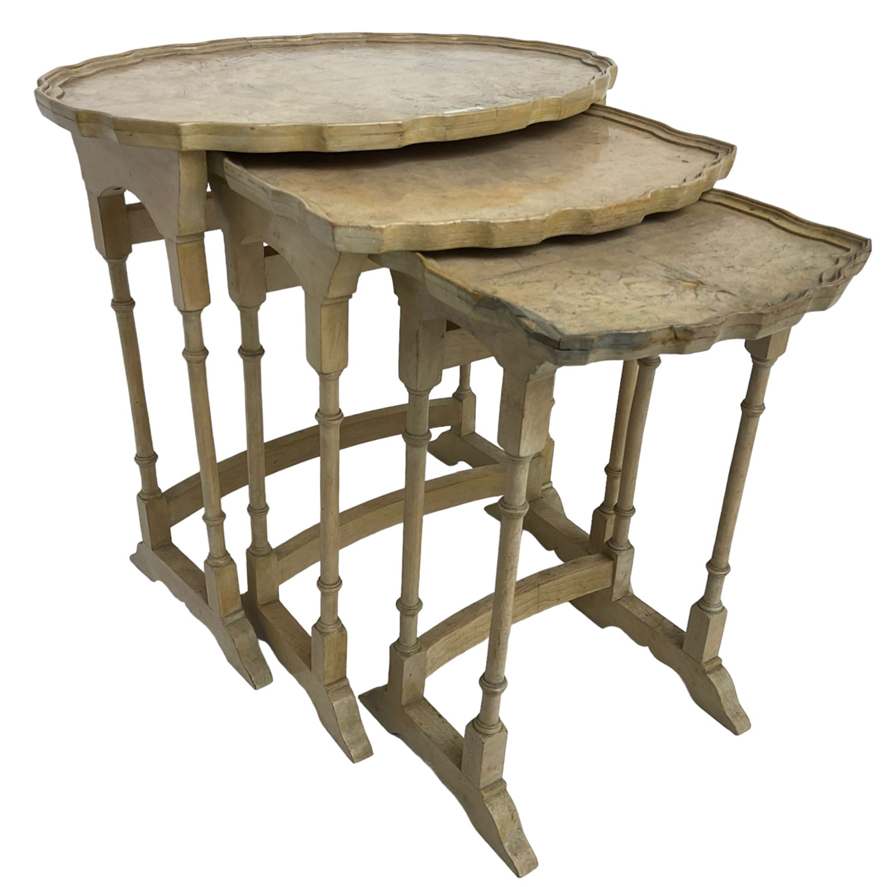 Mid 20th century bleached walnut nest of three tables, oval piecrust tops on turned supports