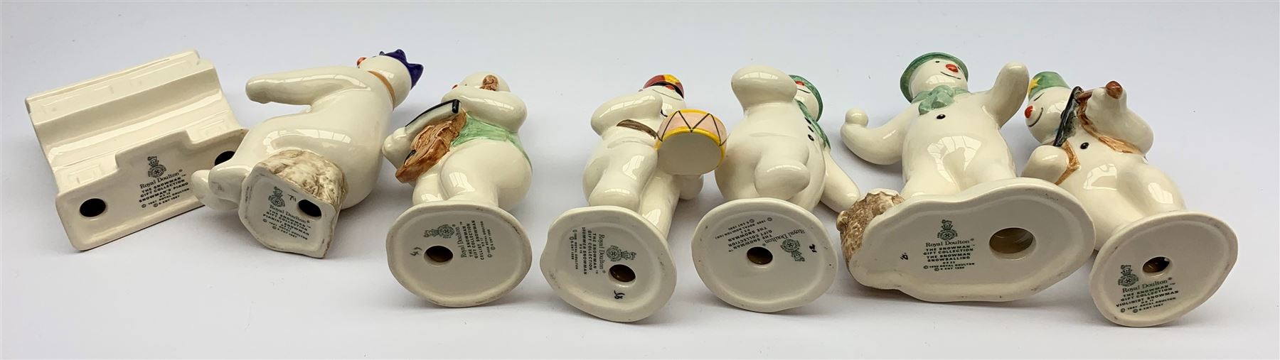 Royal Doulton The Snowman Gift Collection snowman band figures, comprising Cellist Snowman DS17, Violinist Snowman DS11, Drummer Snowman DS15, and Pianist Snowman DS12, plus Snowman's Piano DS13, together with two further figures The Snowman DS2, and The Snowman Snowballing DS22. (7). 