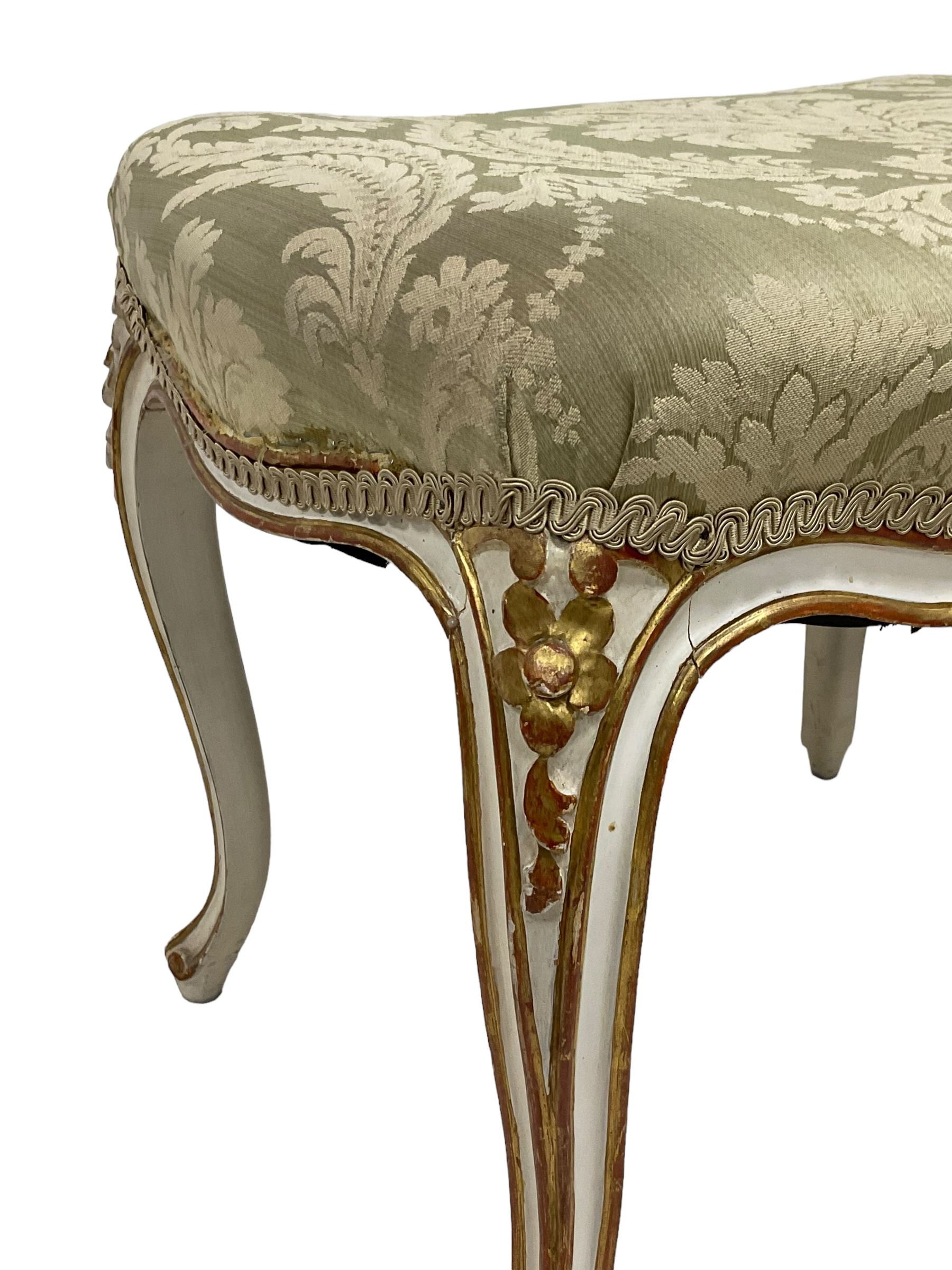 20th century French design parcel gilt and painted dressing table stool, upholstered in sage green damask fabric, shaped form on floral carved cabriole supports, with matching cushion 