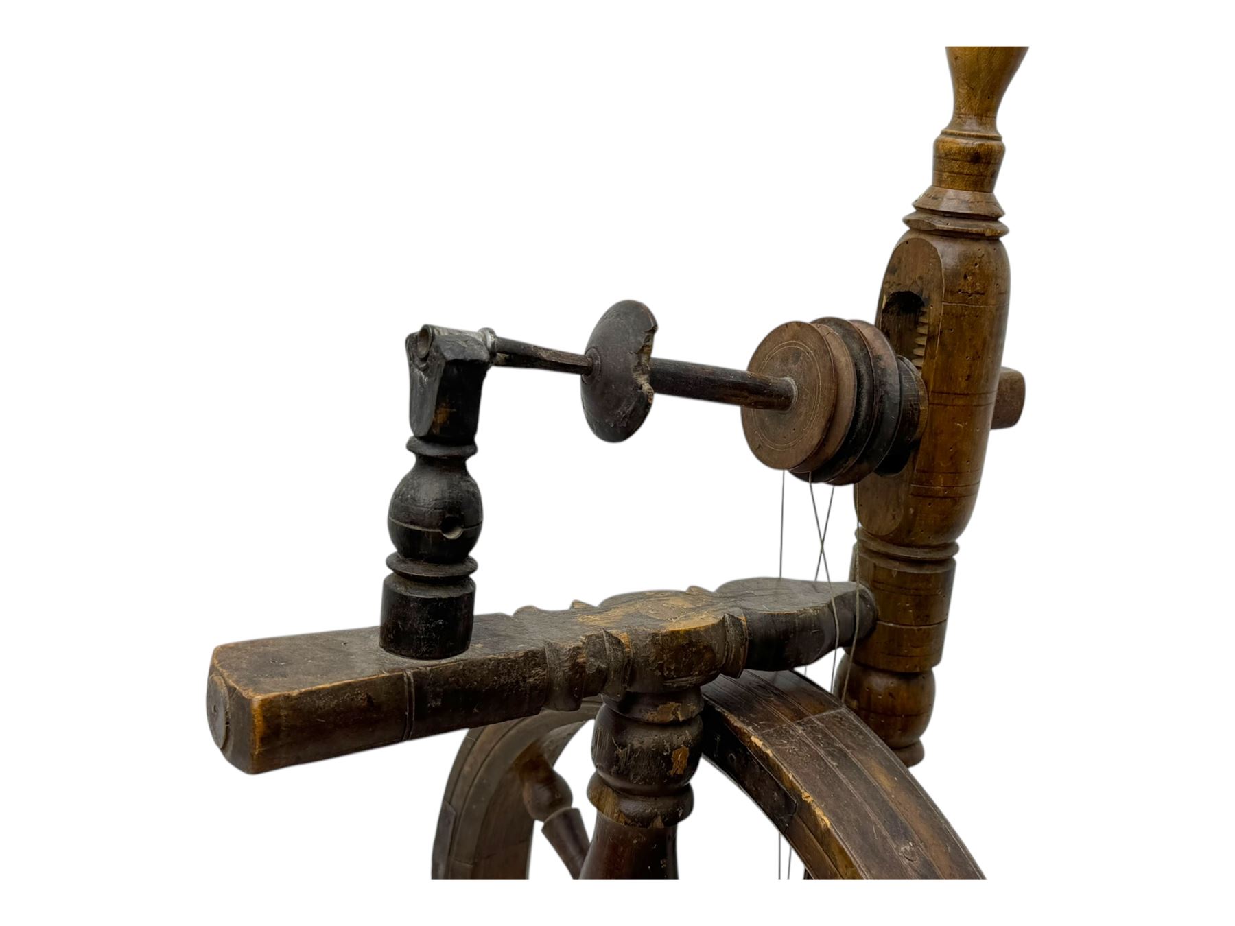 Late 19th century turned beech spinning wheel, upright form with single treadle, triangular base, and a flyer and bobbin assembly surmounted by a turned finial.