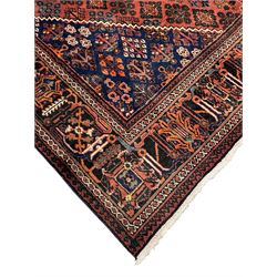 Persian Joshaghan red ground rug, stepped lozenge medallion surrounded by small lozenge motifs, the border decorated with stylised plant motifs within patterned guard stripes