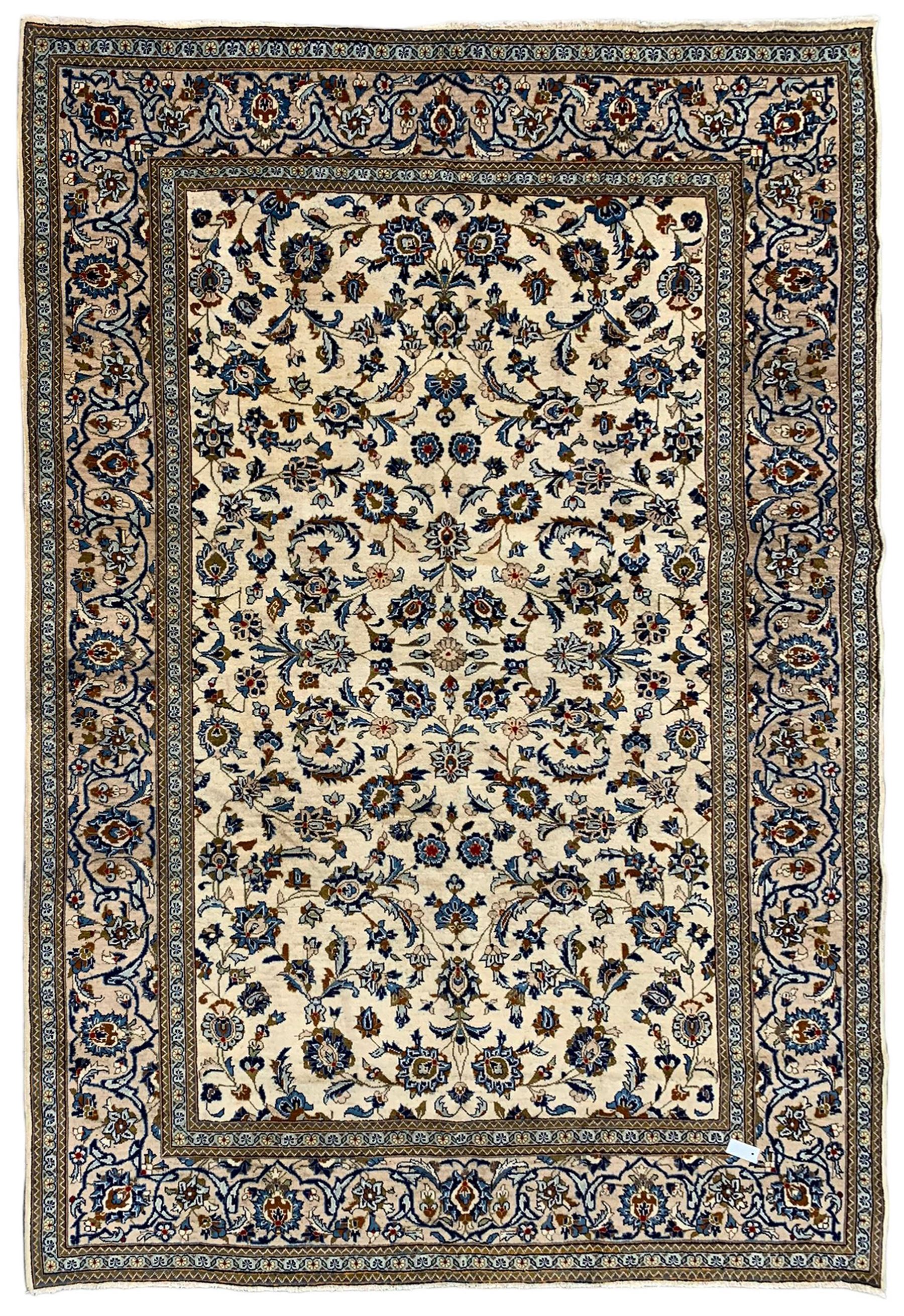 Persian Kashan ivory ground rug, the field decorated with stylised plant motifs and interlacing leafy branches, scrolling border decorated with further plant motifs, floral design guard bands  