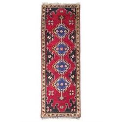Turkish crimson ground rug, the field decorated with four hooked lozenges, trailing border with stylised flower heads 