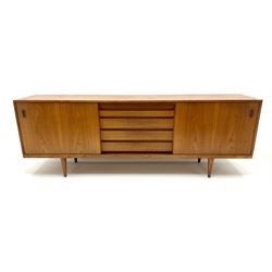 Heals teak sideboard, two sliding drawers enclosing adjustable shelves flanking five graduating drawers, turned tapering supports