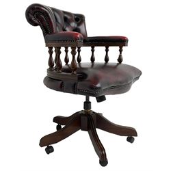 Georgian design swivel desk chair, the rolled back over balustrade support, upholstered in buttoned oxblood leather with studwork border, over a swivel and reclining action with splayed supports and castors
