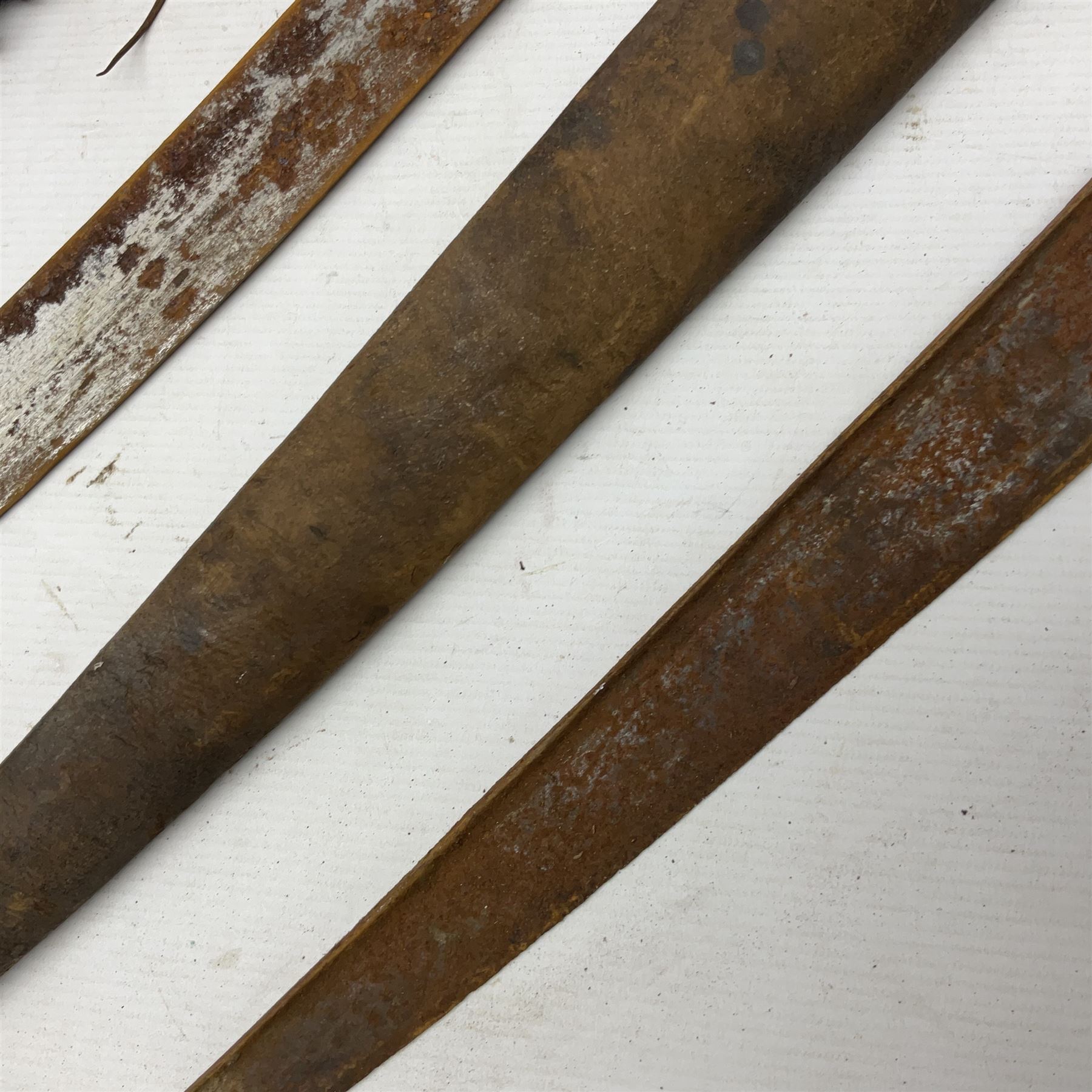 Mandingo sword, the 63cm plain curving steel blade marked with a horses head and the initials G.S.; leather covered grip with metal ribbed spherical pommel; in decorative leather leaf scabbard mounted with tassels and roundels L84cm overall; and a North African flyssa sword in poor condition with wooden scabbard (2)