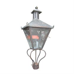 Early 20th century brass and cast iron garden lantern or street light, turned finial over four panel glazed body, cast iron base
