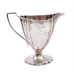 Edwardian silver cream jug, of fluted helmet form, with angular handle and upon shaped foot, hallmarked Birmingham 1905, maker's mark indistinct, together with a set of six Edwardian silver teaspoons and a pair of sugar tongs, all with scrolling embossed decoration and engraved monogram, hallmarked Joseph Rodgers & Sons, Sheffield 1903, within tooled leather fitted case, jug including handle H9cm 