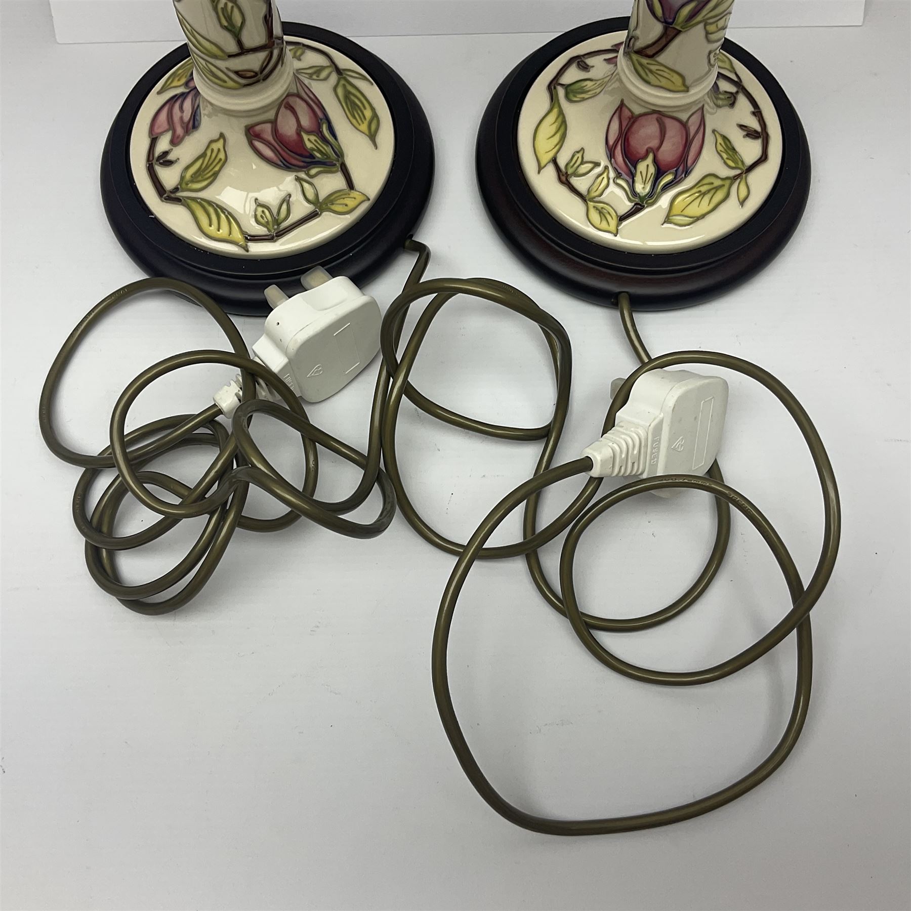 Pair of Moorcroft table lamps of candlestick form in magnolia pattern, with Moorcroft shades, H50cm 
