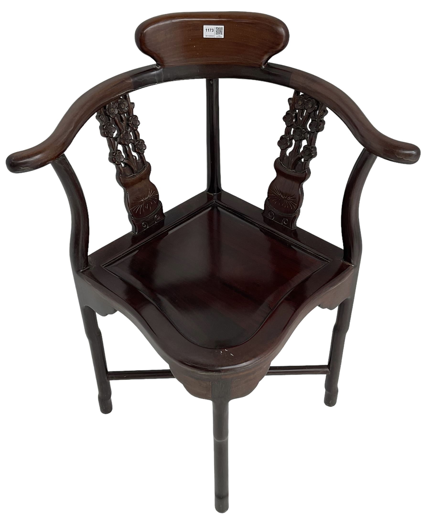 Chinese carved hardwood corner chair, outswept arms over pierced and carved floral splats, raised on shaped cylindrical supports united by X-stretcher