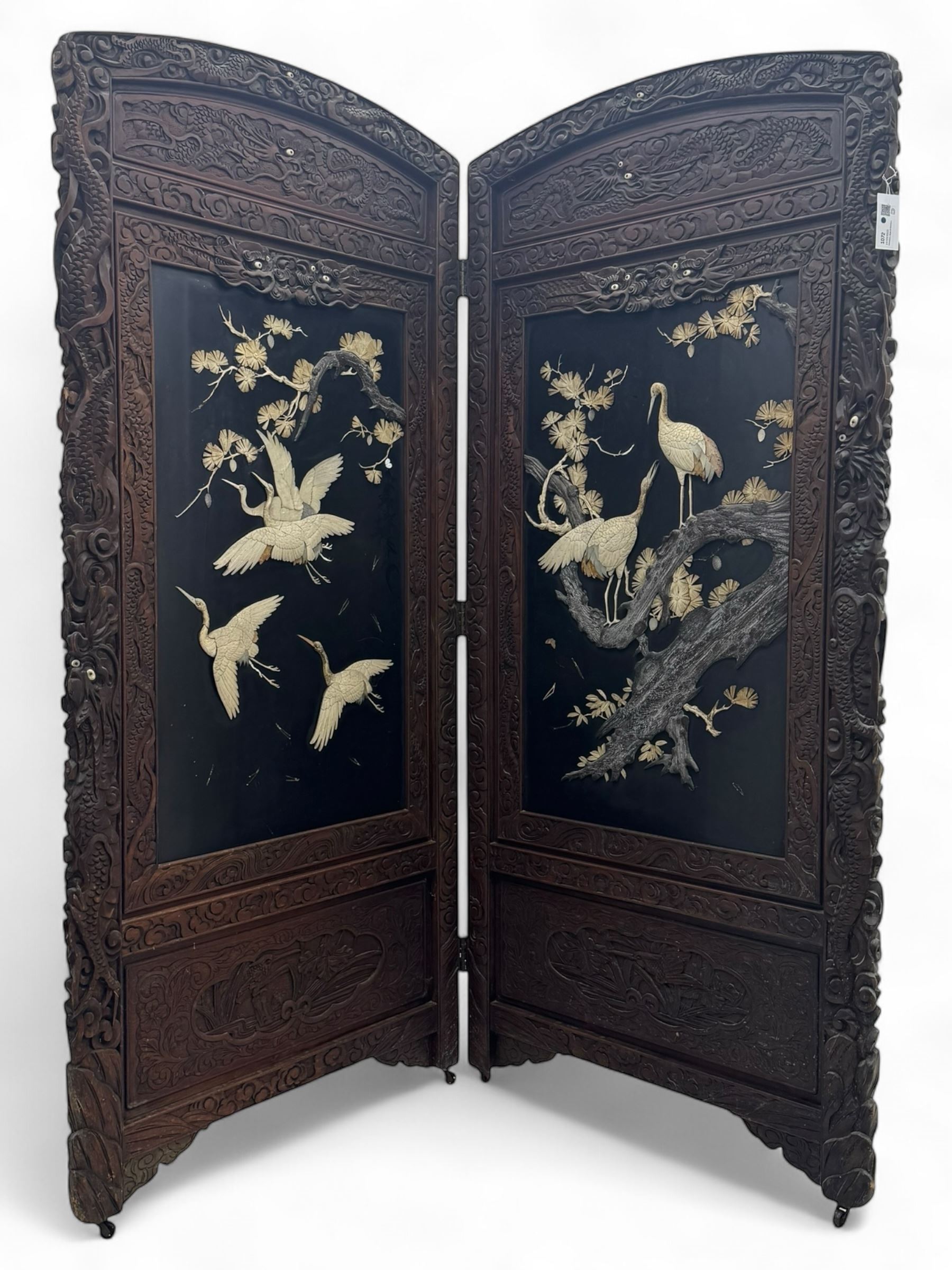 Meiji period (1868–1912), Shibayama lacquer carved hardwood two-fold screen inlaid with mother-of-pearl, bone, and ivory, decorated on one side in high relief and inlaid in a  Shibayama manner with oriental storks flying below flowering branches,  the reverse lacquer panels depicting flowering cherry trees. This item has been registered for sale under section 10 of the APHA Ivory Act.
