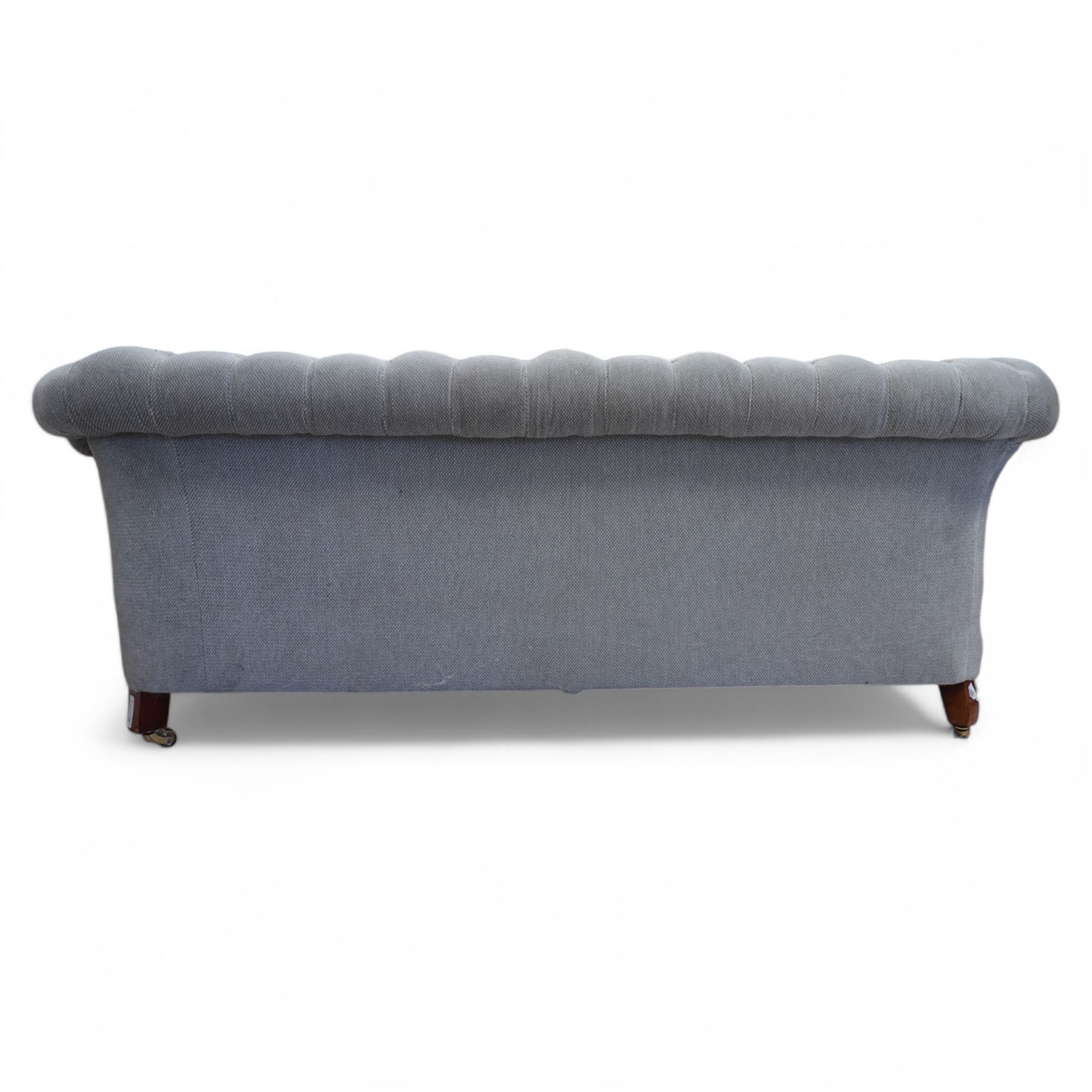 Early 20th century Chesterfield drop-arm two-seat settee, traditional shape with rolled arms and back, upholstered in buttoned pale blue fabric, on ogee block feet with brass castors 