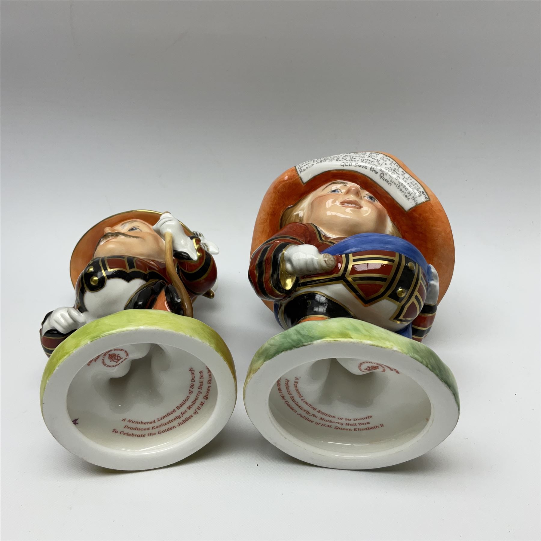 Pair of limited edition Royal Crown Derby Golden Jubilee Mansion House Dwarfs, Tall and Low Dwarf, dressed in Royal Guard uniform, H18cm, exclusive to Mulberry Hall 35/50, each with printed mark beneath, and signed M.E.Reynolds and J Morrison, with makers box. 