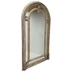 Large painted and gilt arched wall mirror, the frame decorated with scrolling leafy branches, central bevelled mirror mirror surrounded by plain panels, decorated with cartouche mounts 