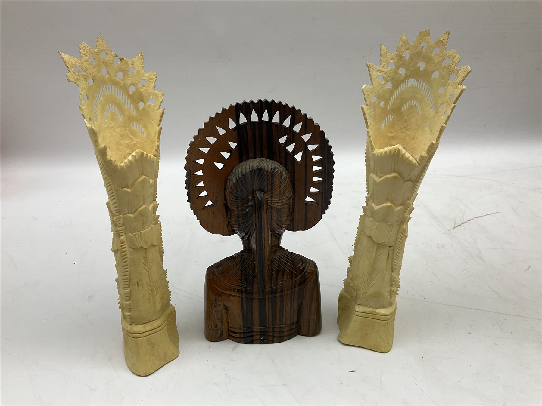 Hardwood bust of an Indoniesian Goddess, carved wearing a pierced headdress, from Klungkung, Bali, H20cm, together with a pair of bone carvings of deity figures, and a carved wood Netsuke in the form of a Chinese dragon