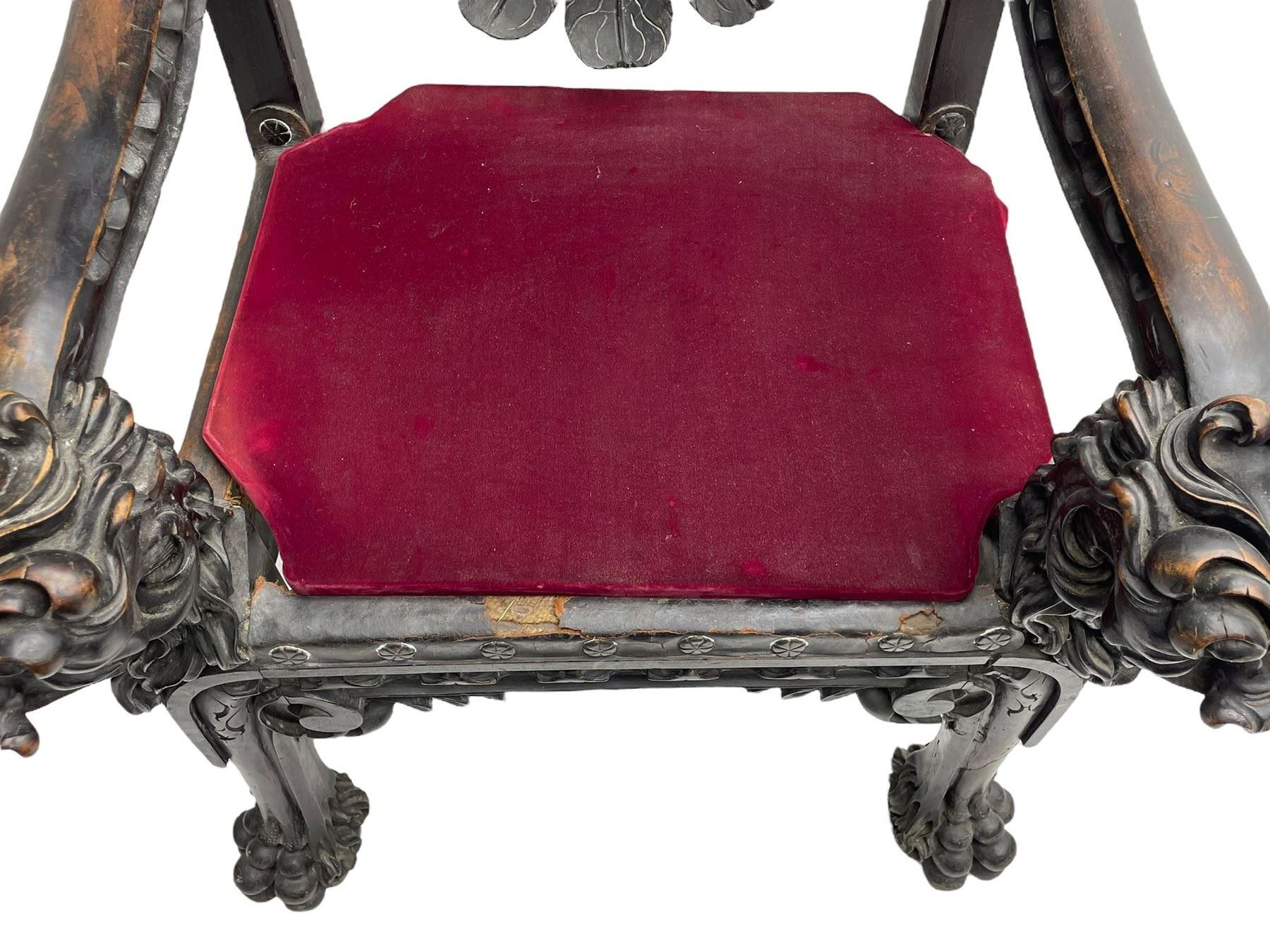 Grand mid-to-late 19th century heavily carved beech framed throne chair, the crown pediment carved with flower heads and cross finial, scroll and acanthus carved upright supports with twin perching griffin back enclosing etched leather work heraldic shield with castle and lion motifs over splayed feathers, flower head carved down sweeping arms with grotesque carved terminals, the seat rails carved with further flower heads on moulded supports with oversized ball and claw carved feet

Provenance: A very similar chair was used in the filming of Stanley Kubrick's 'Eyes Wide Shut' (1999)
