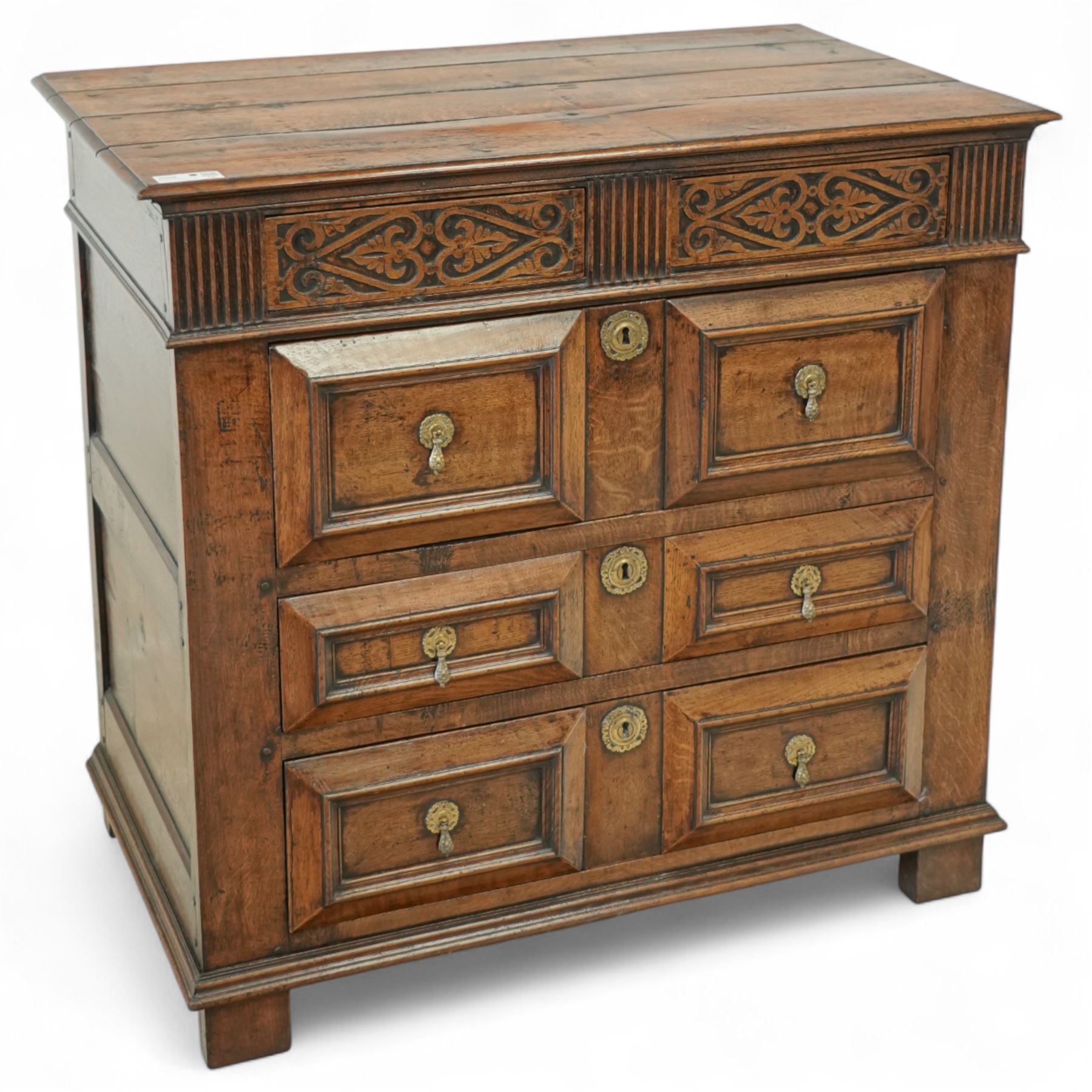 John Nethercott & Co - late 20th century hand-made oak 17th-century design chest of drawers, rectangular pegged and planked top above scrollwork carved frieze concealing two drawers, over three drawers, all with raised rectangular moulding and drop handles, raised on stile feet, the back with dated label for John Nethercott & Co