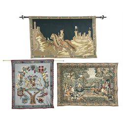Three tapestries comprising 20th century wool tapestry panel of a medieval nobleman upon a horse with a castle in the distance, together with a smaller tapestry depicting The English Coat of Arms, both hung on rails, and further depicting village scene, largest approx 132cm x 95cm