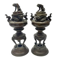 Pair of oriental brass twin-handled incense burners, decorated in high relief with dragon and foo dog masks, the removable pierced cover with foo dog final, upon three scroll feet and circular base, H21.5cm