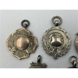 Seven early 20th century silver gold faced cartouche fobs, to include a circular example, with rose gold border and cartouche within an embossed yellow gold border, engraved verso, and a double sided example, all hallmarked with various dates and makers
