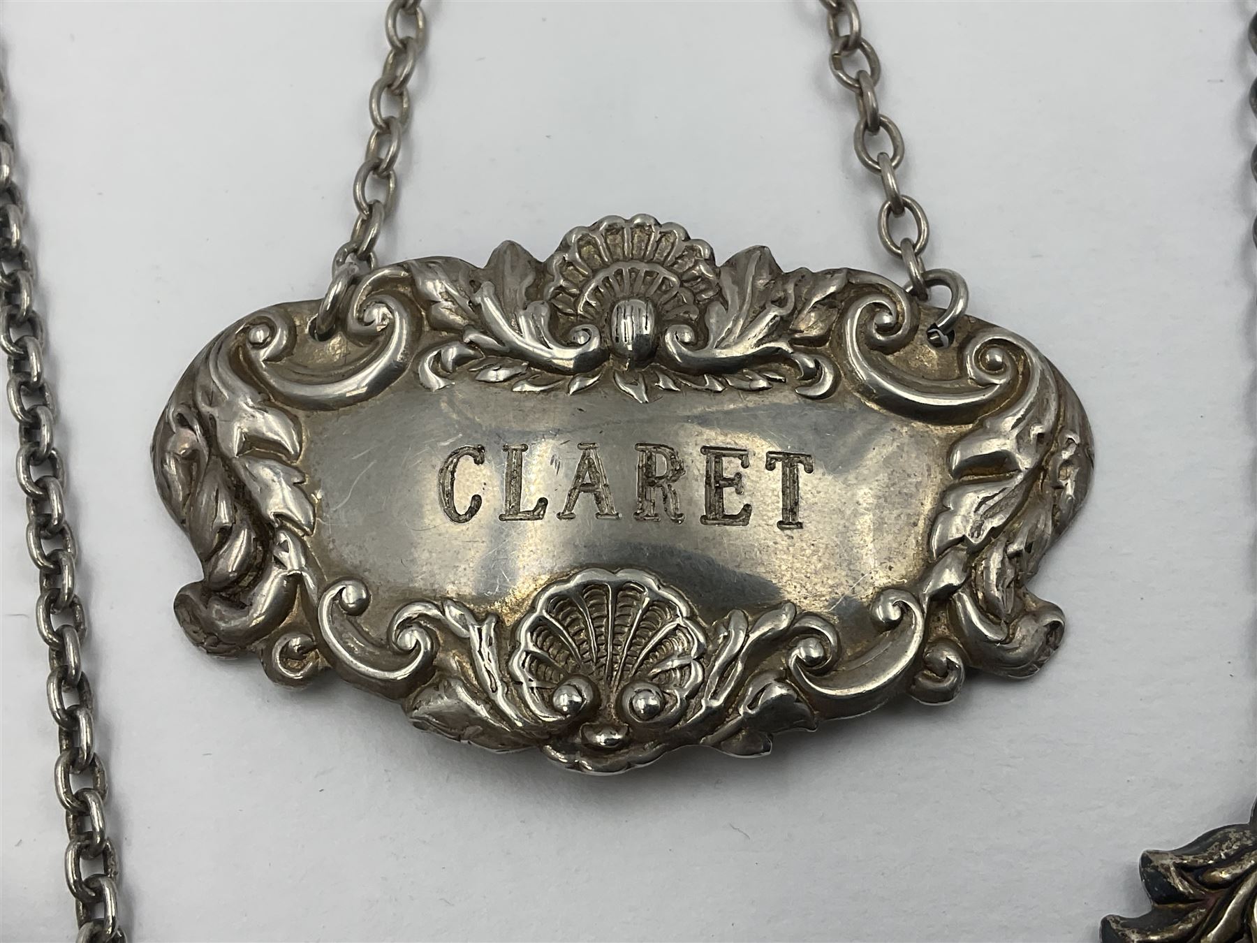 Five modern silver decanter labels, to include two sherry examples, embossed with scrolls and fruits, hallmarked W I Broadway & Co, Birmingham 1991 & 1997, a similar claret example, hallmarked S J Rose & Son, Birmingham 1973, and two plain shaped port and burgundy examples, hallmarked C Robathan & Son, Birmingham 1997 and A Haviland-Nye, London 1968