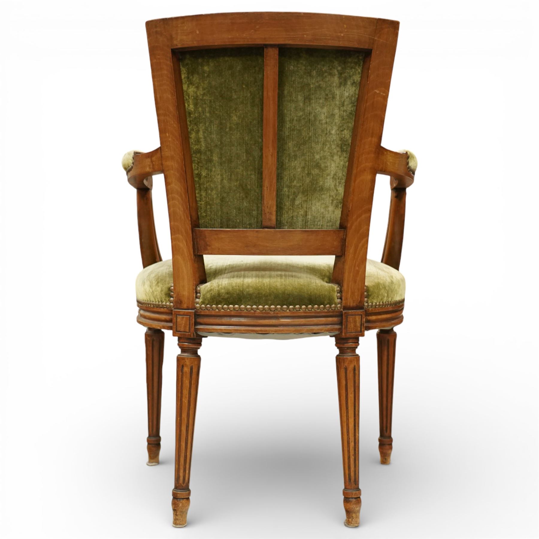 French Louis XVI style walnut armchairs, rectangular upholstered backs with nailhead trim, padded seats upholstered en suite, out-swept arms with upholstered pads, fluted supports with carved rosettes to the knees, on turned and fluted tapering legs