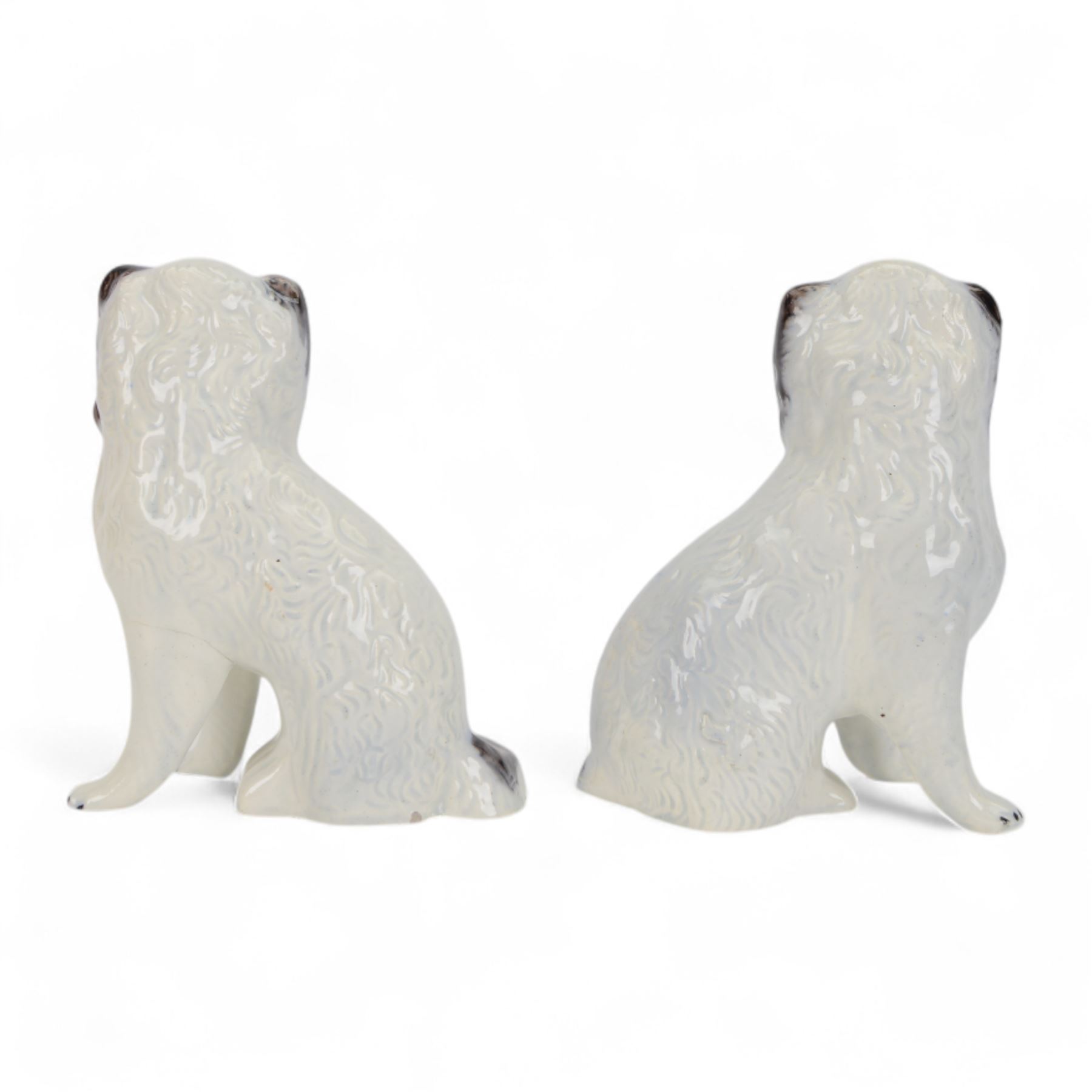 Pair of 19th century slip moulded pottery spaniels, circa 1840-1850, possibly Scottish, modelled with free standing forelegs and moulded fur with dark brown detailing and yellow glazed collars and padlocks upon a white ground, H17.5cm