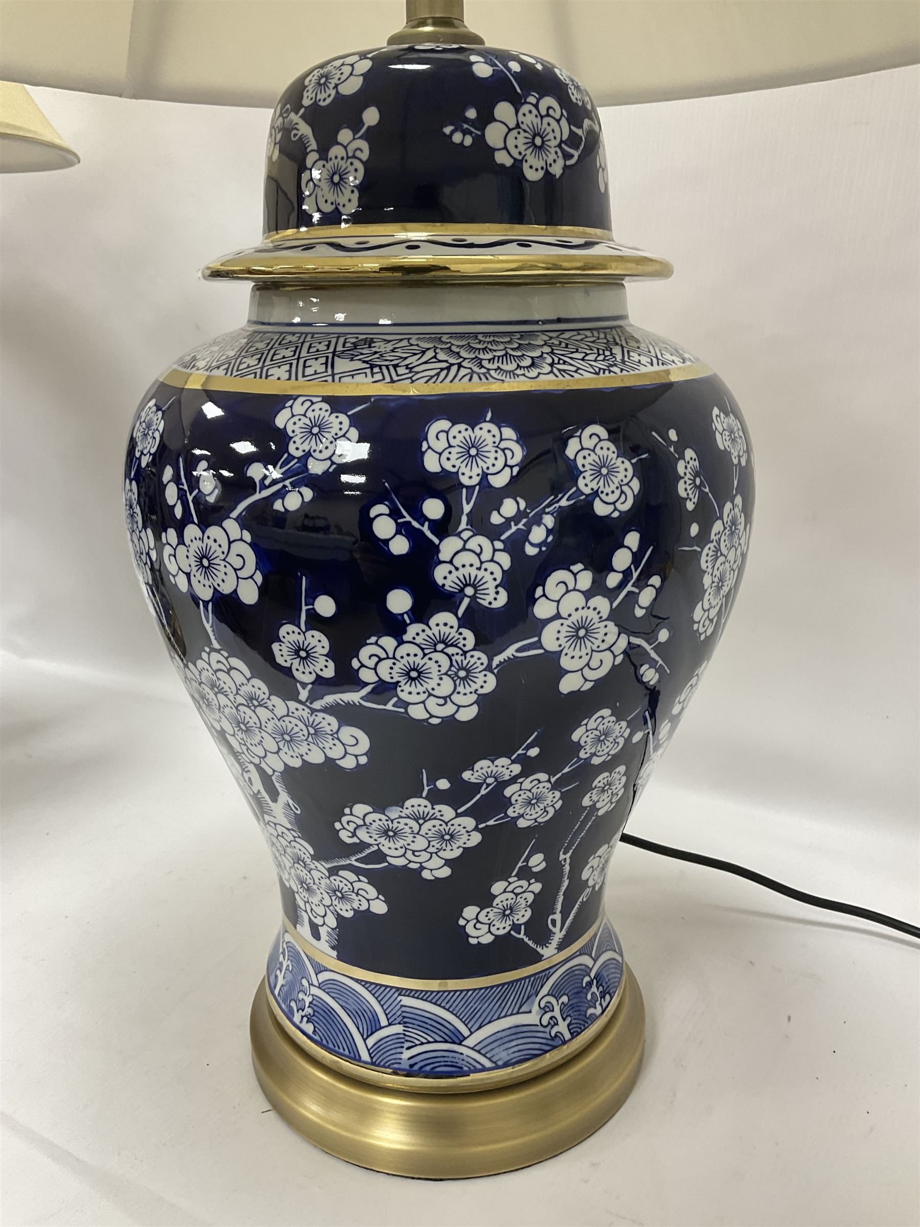 Pair of blue and white table lamps, each of baluster form, decorated with prunus blossom, within stylised borders, raised upon circular gilt base, excluding fittings H48cm
