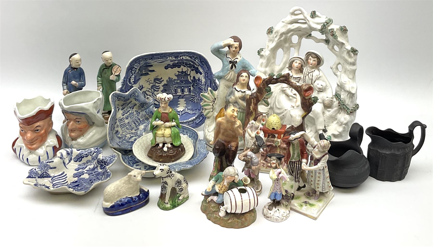 Two 19th century blue and white pickle dishes, each decorated in a variant of the Willow pattern, 19th century blue and white Willow pattern dessert dish, further Willow pattern dish, two black basalt jugs, small Victorian cockle dish, plus a group of Victorian and later figures, to include two Staffordshire arbour groups, one with beehive, Staffordshire style model of a sheep, two Sitzendorf monkey band figures, a Continental figure group modelled as a dancing couple, Atlas China figure of a Satyr, two jugs modelled as Punch and Judy, Rd no 139844, etc. 