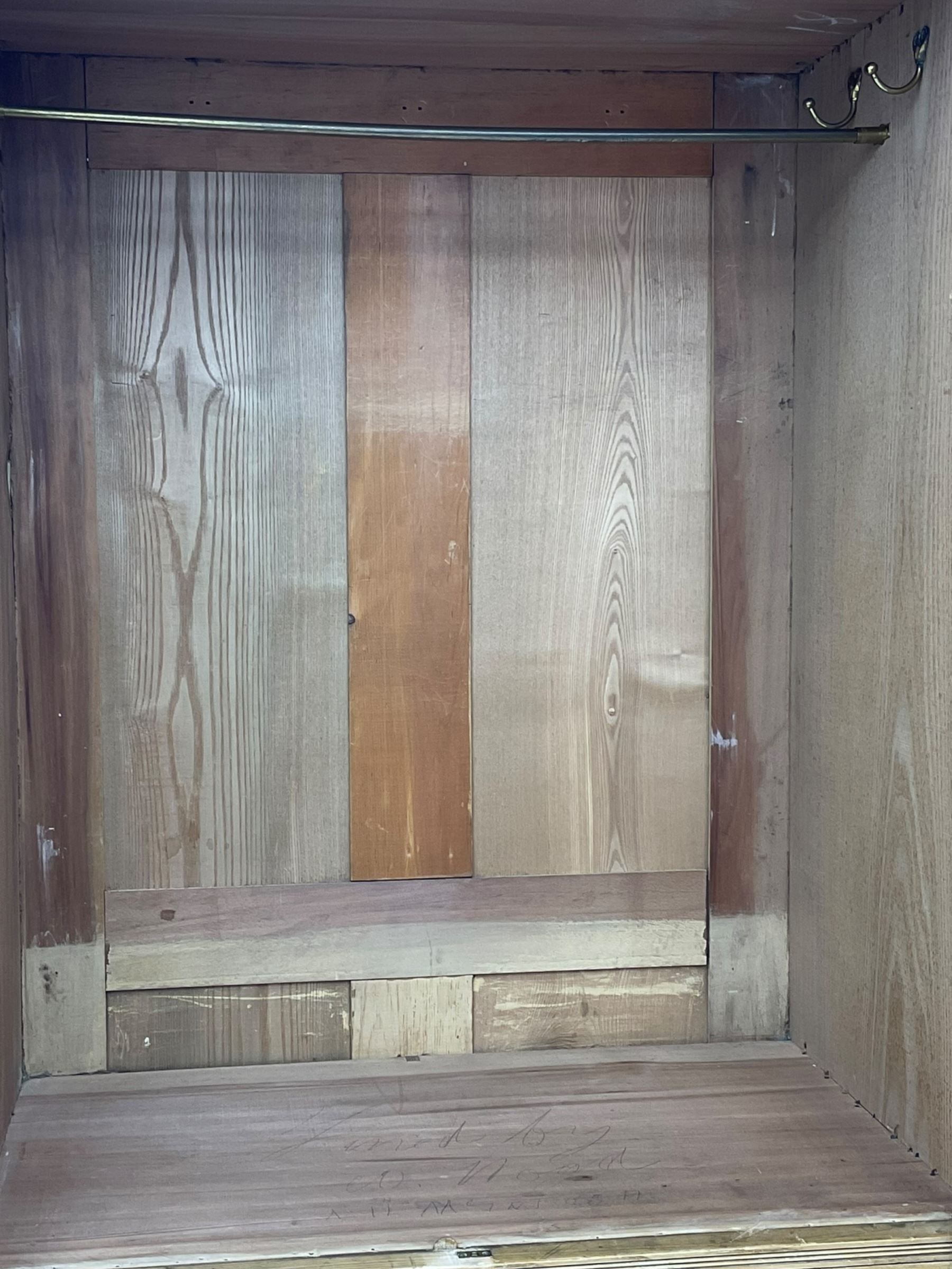 Late 19th century ash combination wardrobe, projecting cornice over foliage carved frieze, the left-hand upright enclosed by mirror glazed door, the right-hand side fitted with double panelled cupboard over two short and three long drawers, the upper panels carved with curled leaves and central scroll cartouche, on bracketed plinth 