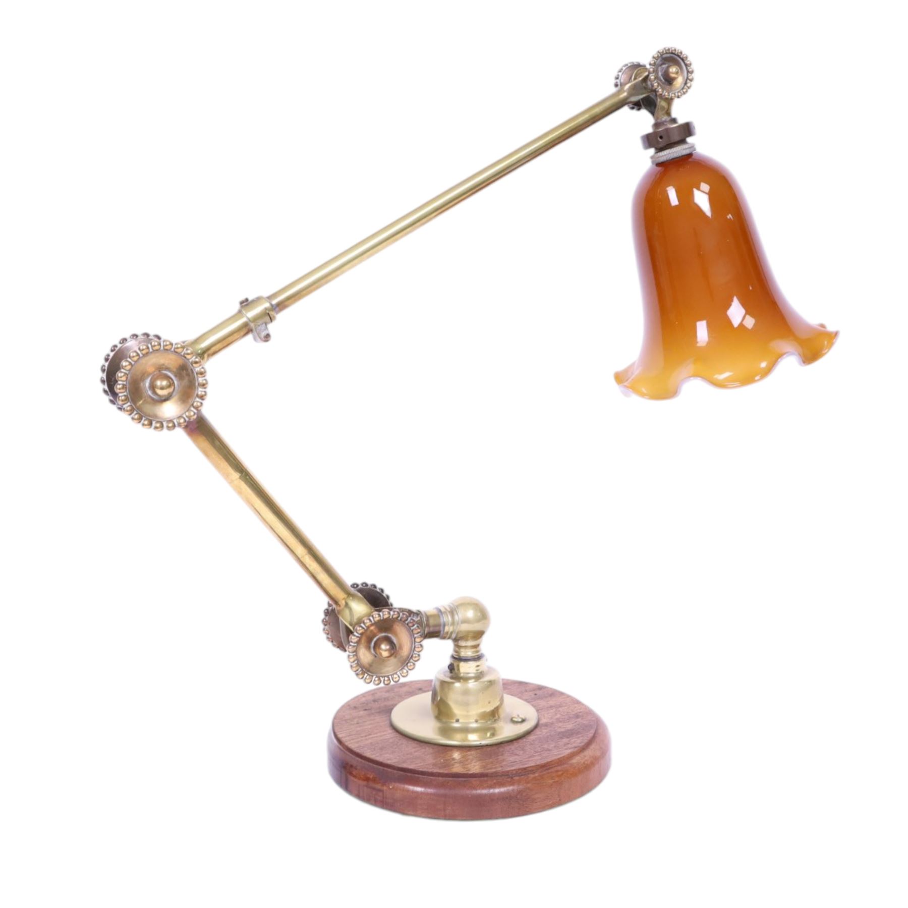 John Dugdill, early 20th century brass angle poise desk lamp, circa 1930's, with daisyhead joints and amber coloured lampshade, upon a circular wooden base 