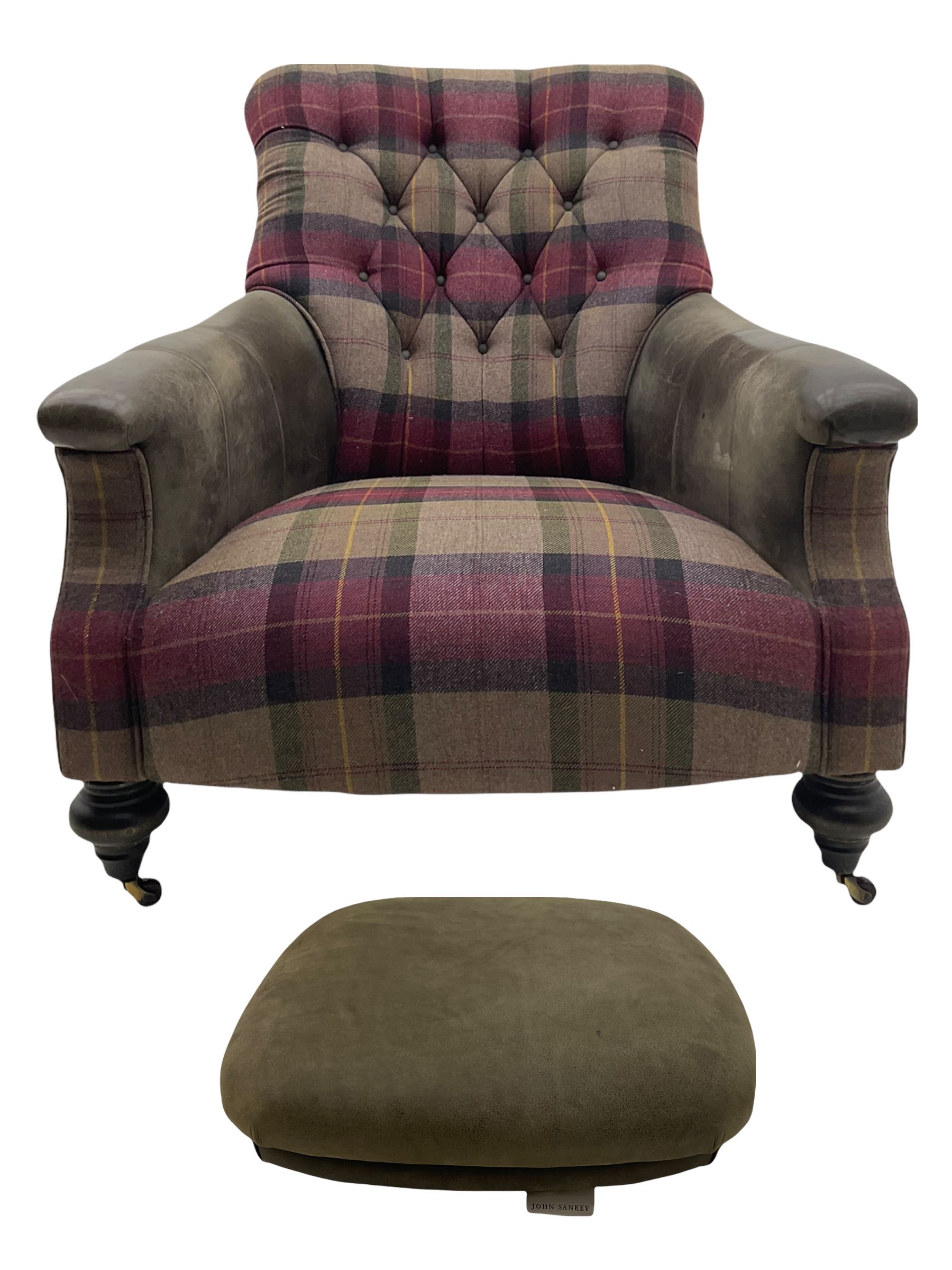 John Sankey - low armchair, buttoned back upholstered in tartan patterned fabric with contrasting grey leather, raised on turned and ebonised front feet with brass and ceramic castors, with matching foot stool